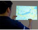 Durch den am Körper getragenen Projektor kann jede Oberfläche als Interaktionsfläche dienen. So kann man sich Karten der Umgebung anschauen und mit natürlichen Gesten modifizieren.