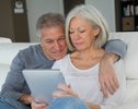 Senior couple sitting in sofa with electronic tablet